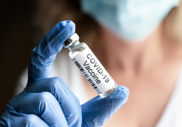 Female doctor holds bottle with COVID19 coronavirus vaccine in laboratory