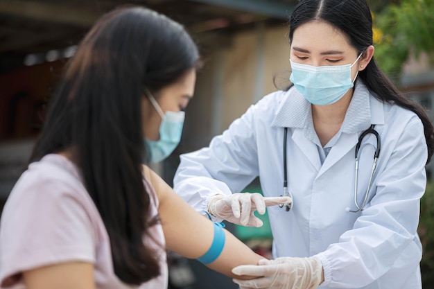 Female doctor injecting antiviral medication to patient. Woman in mask receives COVID-19 vaccine or influenza at the field hospital