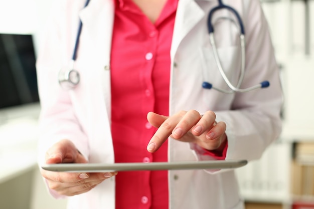 Female doctor is holding modern tablet and using remote telemedicine application