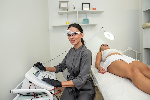 Female doctor is preparing for a cosmetology procedure with electroepilation