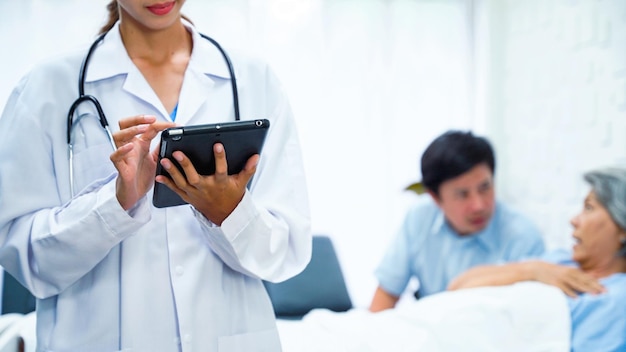 Female doctor is using a tablet to record the results of an elderly female patient