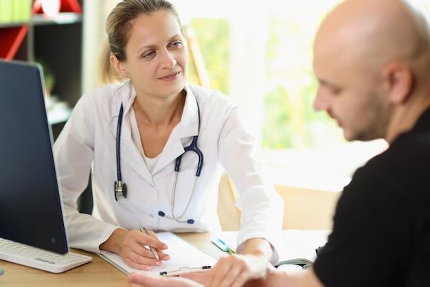 Female doctor listens to her patient while sitting at office desk in medical clinic healthcare