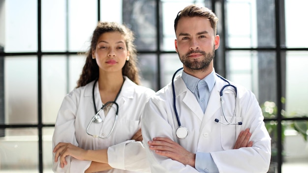 A female doctor and a male doctor are standing in the office with their arms crossed