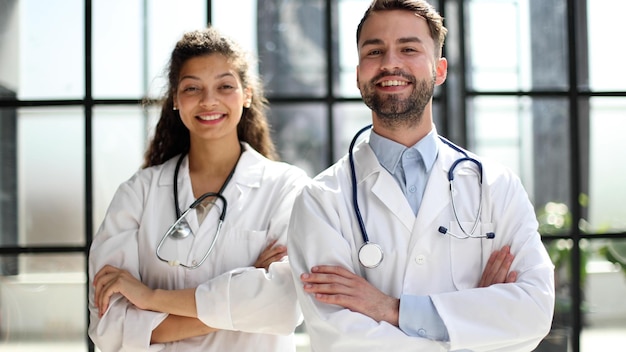 A female doctor and a male doctor are standing in the office with their arms crossed