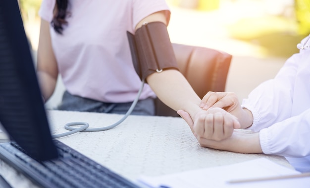 Female Doctor Measuring Blood Pressure Of women patient social service in  local village Thailand.