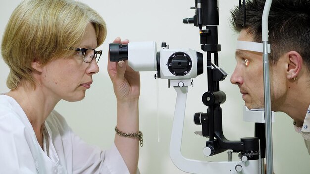 Photo female doctor optometrist ophthalmologist with non contact tonometer is cheking patients vision