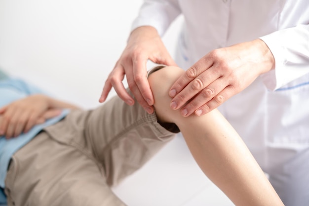 Female doctor orthopedist examines young boys knee at the hospital or clinic Trauma or pain