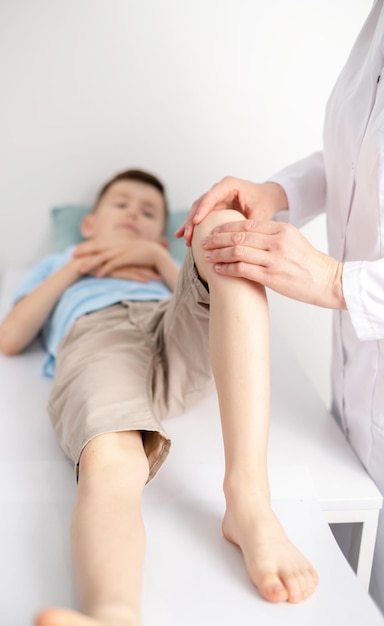 Female doctor orthopedist examines young boys knee at the hospital or clinic Trauma or pain