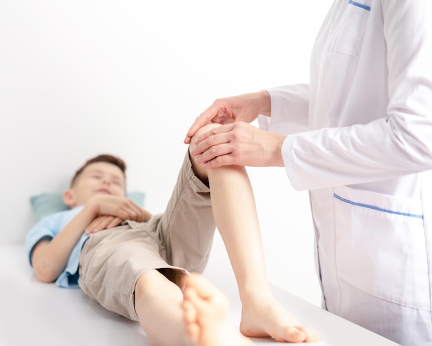 Female doctor orthopedist examines young boys knee at the hospital or clinic Trauma or pain