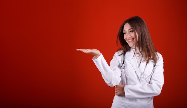 Female doctor pointing at something on a red background