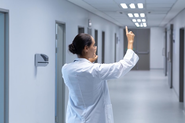 Female doctor pretending to touch an invisible screen in the corridor at hospital