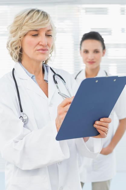 Female doctor reading reports with colleague in hospital