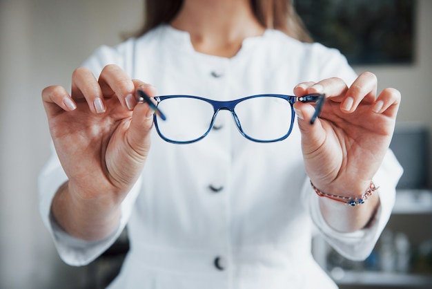 Female doctor showing the blue glasses by holding it in two hands.