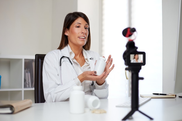 Female doctor showing pills and recording a video vlog