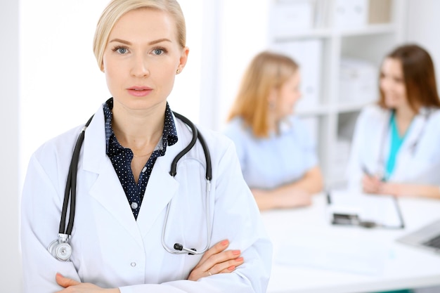 Female doctor smiling on the background with patient and his physician in hospital