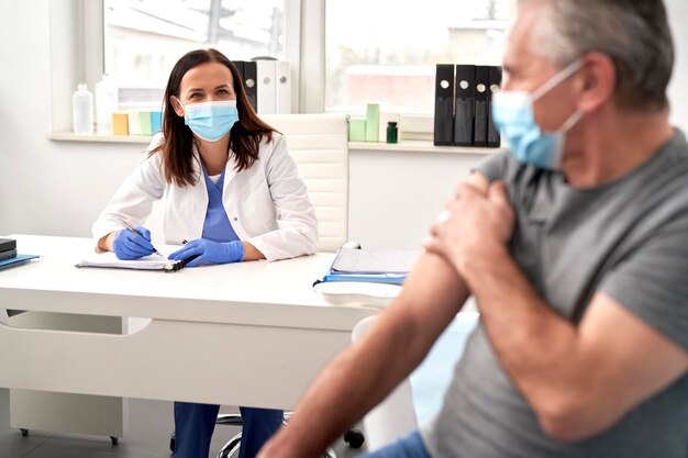 Female doctor talking to senior after vaccination