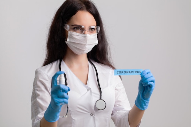 Female doctor in uniform holding a paper signboard lettering coronavirus