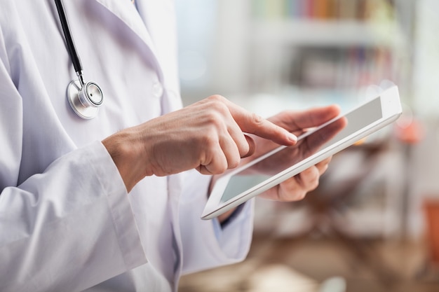 Female doctor using digital tablet, close up on hands