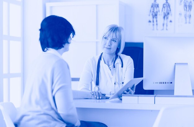 Female doctor using digital tablet talking with patients