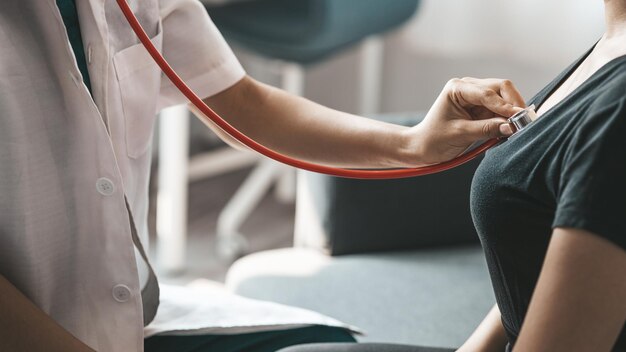 A female doctor using a stethoscope she is examining the patient in the examination room and informing the patients about treatment guidelines and prescribing medicines Disease examination concept