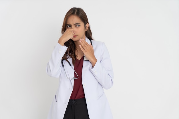 Female doctor wearing white suit uniform feels uncomfortable because she smells bad smell by coverin...