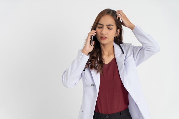 A female doctor wearing a white uniform confused with a distressed gesture while making a phone call