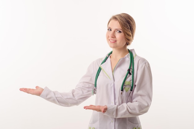 Female doctor on a white background with a phonendoscope points to something