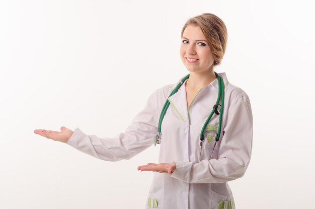 Female doctor on a white background with a phonendoscope points to something