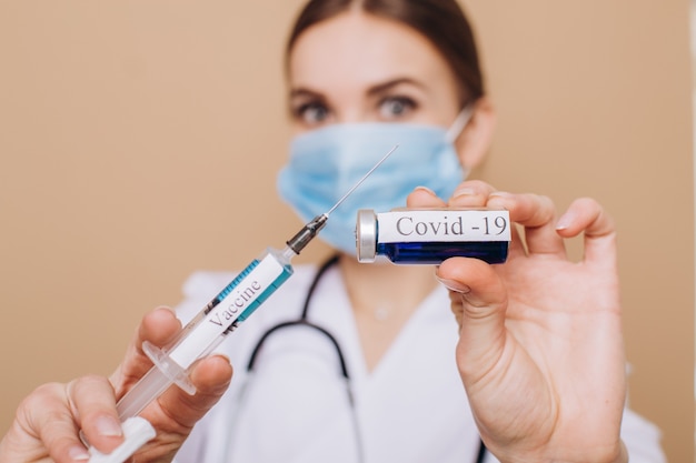 female doctor in a white coat holding a syringe with covid19 vaccine closeup Vaccination concept