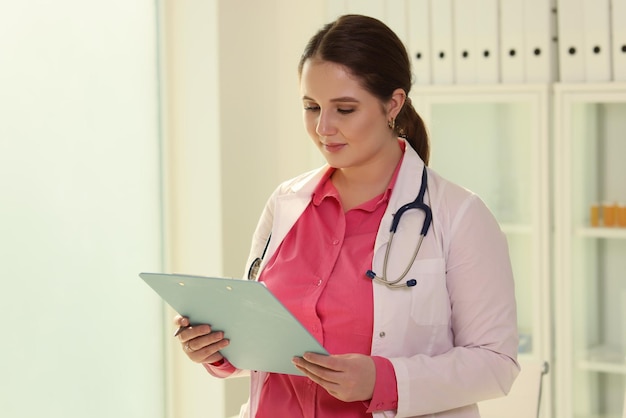 Female doctor with stethoscope checks treatment plan for patient on clipboard brunette woman