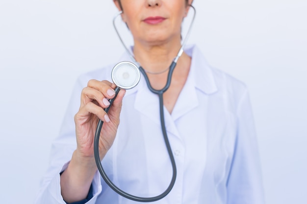 Female doctor with stethoscope, close up over white wall