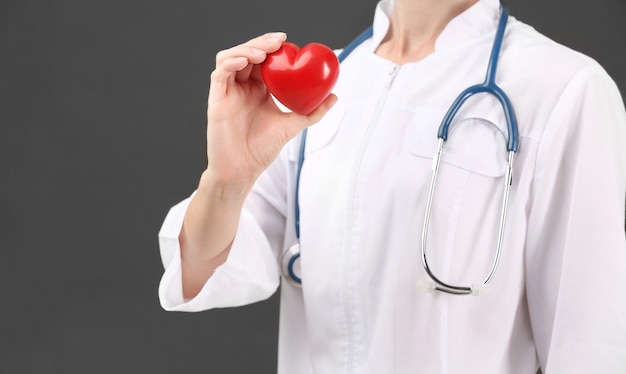 Female doctor with stethoscope holding heart