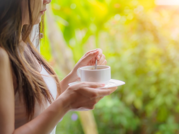 Female drinking a cup of coffee at the garden in the morning