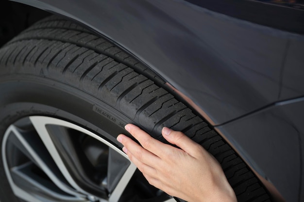 Female driver hands inspecting wheel tire of her new car Vehicle safety concept