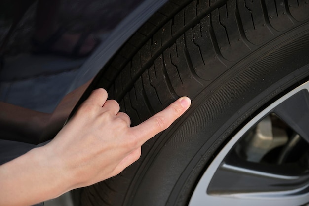 Female driver hands inspecting wheel tire of her new car Vehicle safety concept