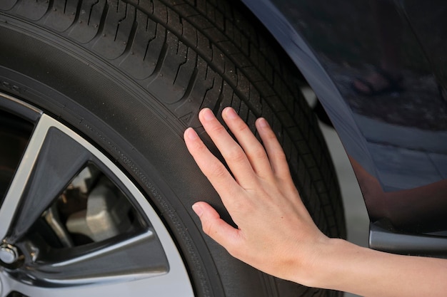 Female driver hands inspecting wheel tire of her new car Vehicle safety concept