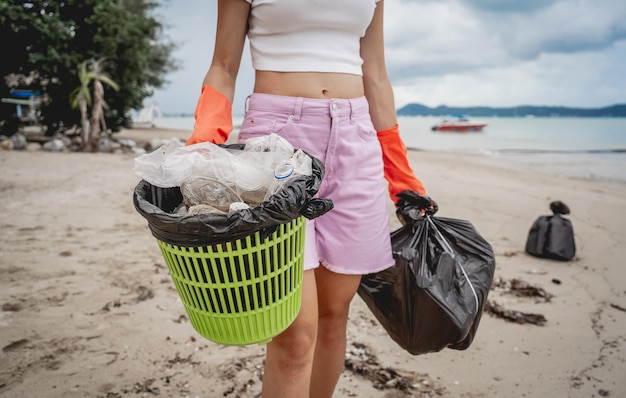 A female ecologist volunteer cleans the beach on the seashore from plastic and other waste