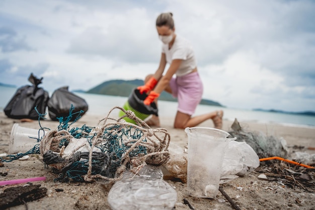 A female ecologist volunteer cleans the beach on the seashore from plastic and other waste