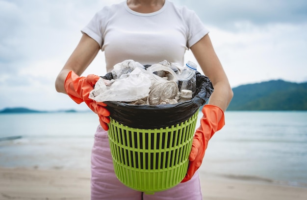 A female ecologist volunteer cleans the beach on the seashore from plastic and other waste