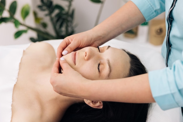 Female enjoying relaxing face massage in cosmetology spa centre body care skin care