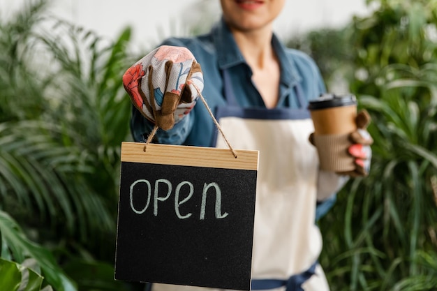 Female entrepreneur holding open sign in hands in floral store