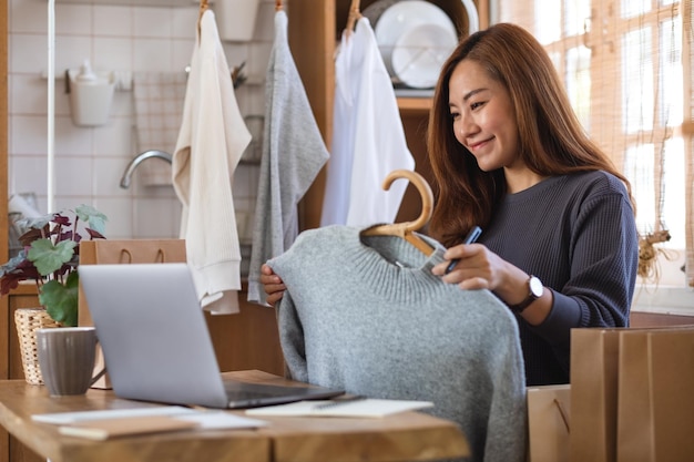 A female entrepreneur using laptop computer for selling clothes online or review product on social media at home