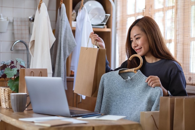 A female entrepreneur using laptop computer for selling clothes online or review product on social media at home