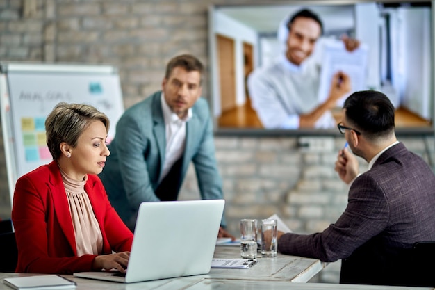 Female entrepreneur using laptop while having business video conference meeting in the office