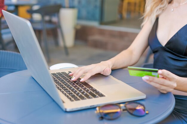 Female entrepreneur working on computer in cafe doing online shopping with credit card in hand