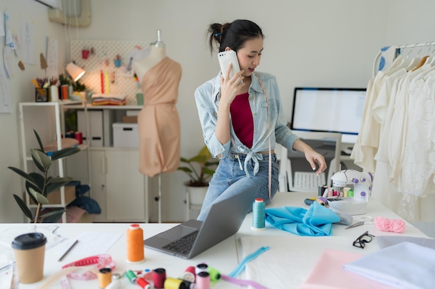 Female entrepreneur working mobile chat in tailoring studio