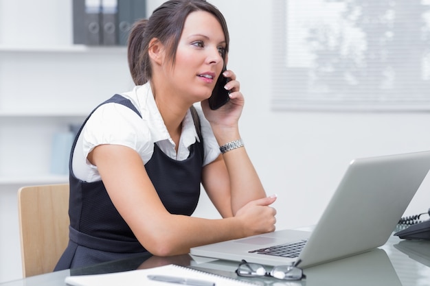 Female executive on call in front of laptop at desk