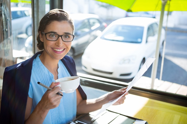 Female executive looking at document while having coffee