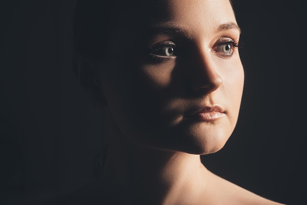 Female face. Woman mystery. Portrait of confident lady with in dark shade isolated on black background. Tenderness tranquility. Beauty enhancement.