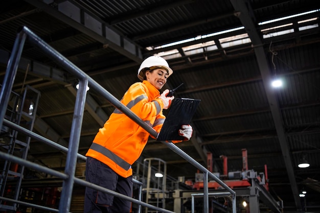 Female factory worker or supervisor operating production process via radio communication